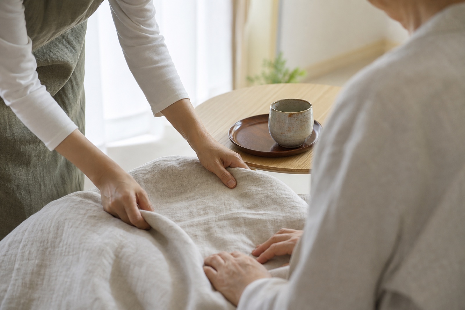 自然光の中で寝具を整える訪問介護の手元